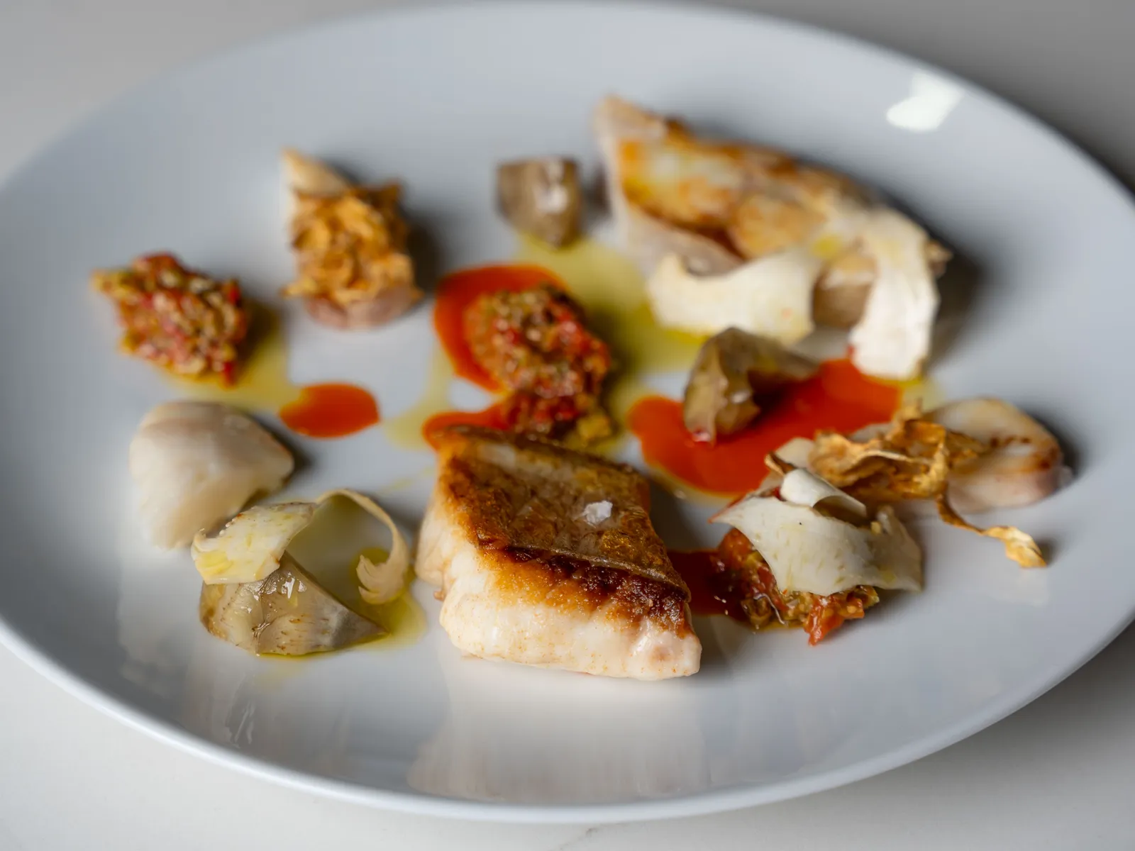 Roasted fish with artichokes and red pepper sauce, plated at Lilli in Las Vegas Chinatown