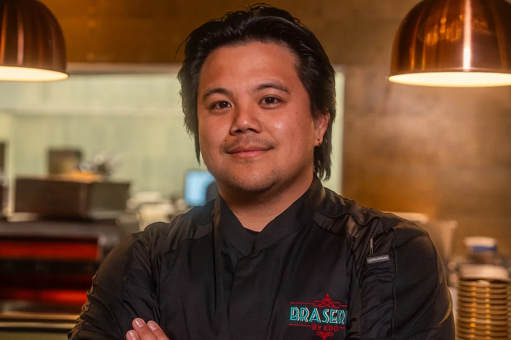 A chef in a black jacket standing in a restaurant kitchen