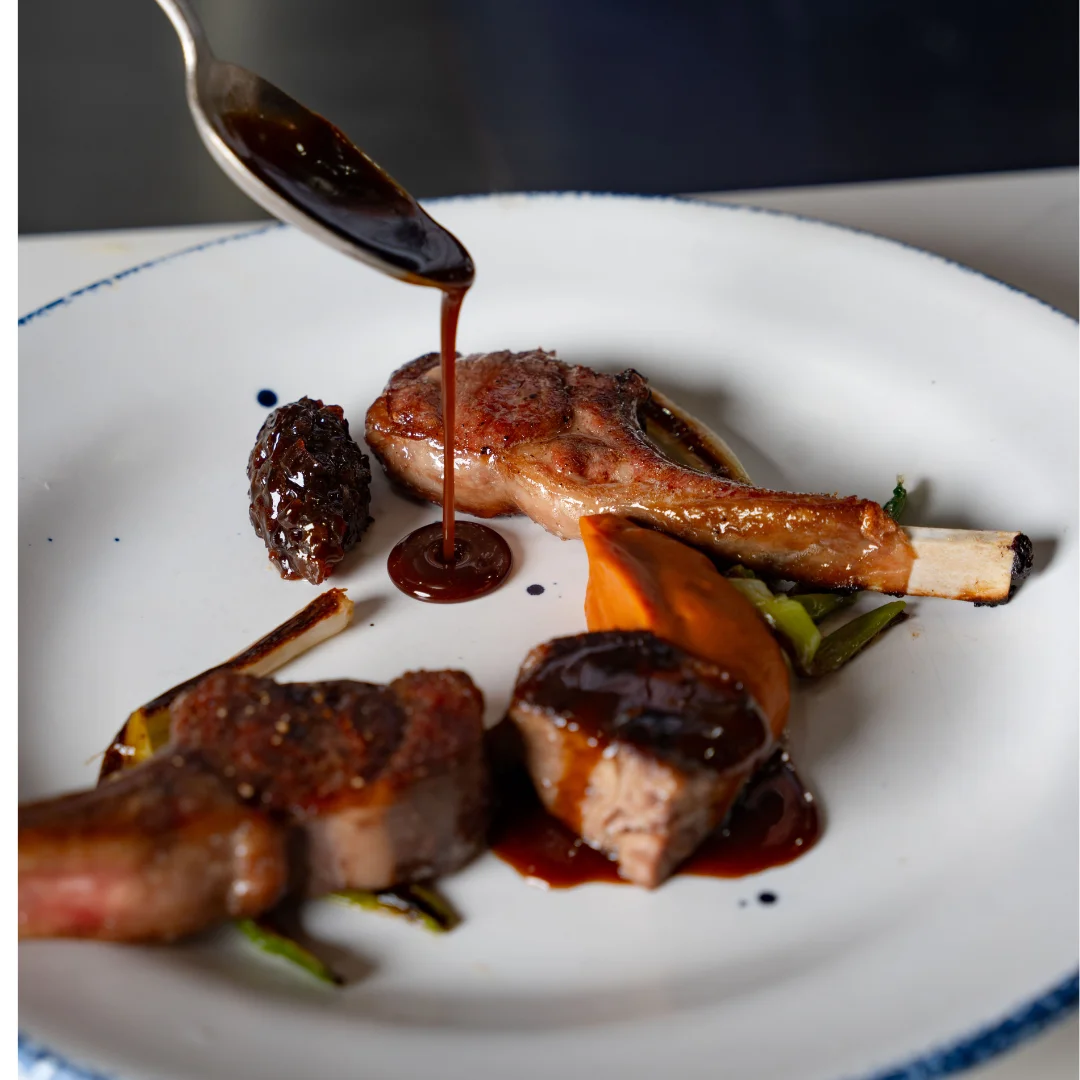 Sauce spooned over a rack of lamb with morels