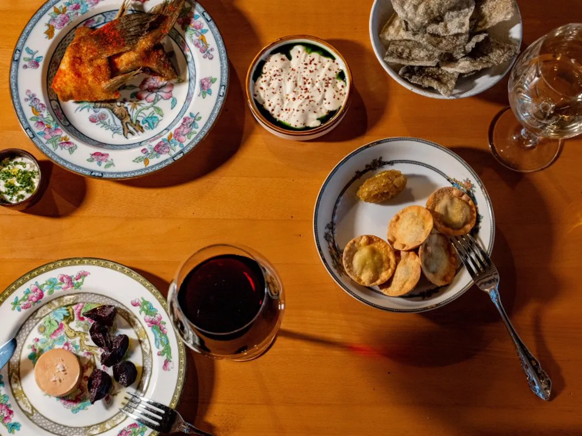 Small plates from Lilli on a wooden table, including fried fish, foie gras with beets, and tortellini
